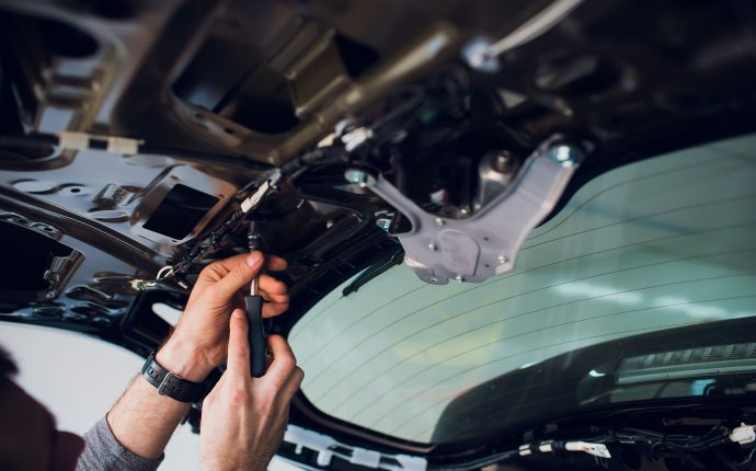 Mechanic installing car central door lock motor.