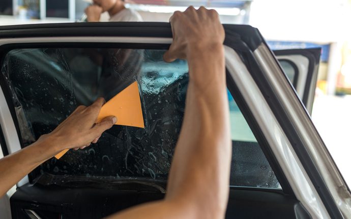 Technician Installing car window tint. Car window tinting series. Car window tinting specialist install car film windscreen.