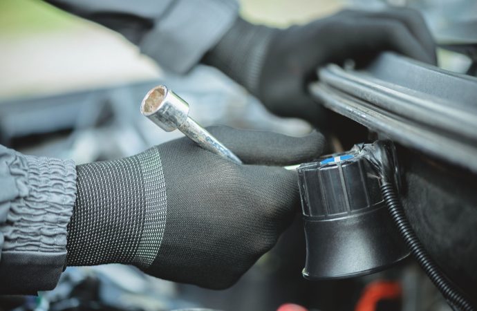 Worker is installing a car alarm siren under the hood of a car close up.